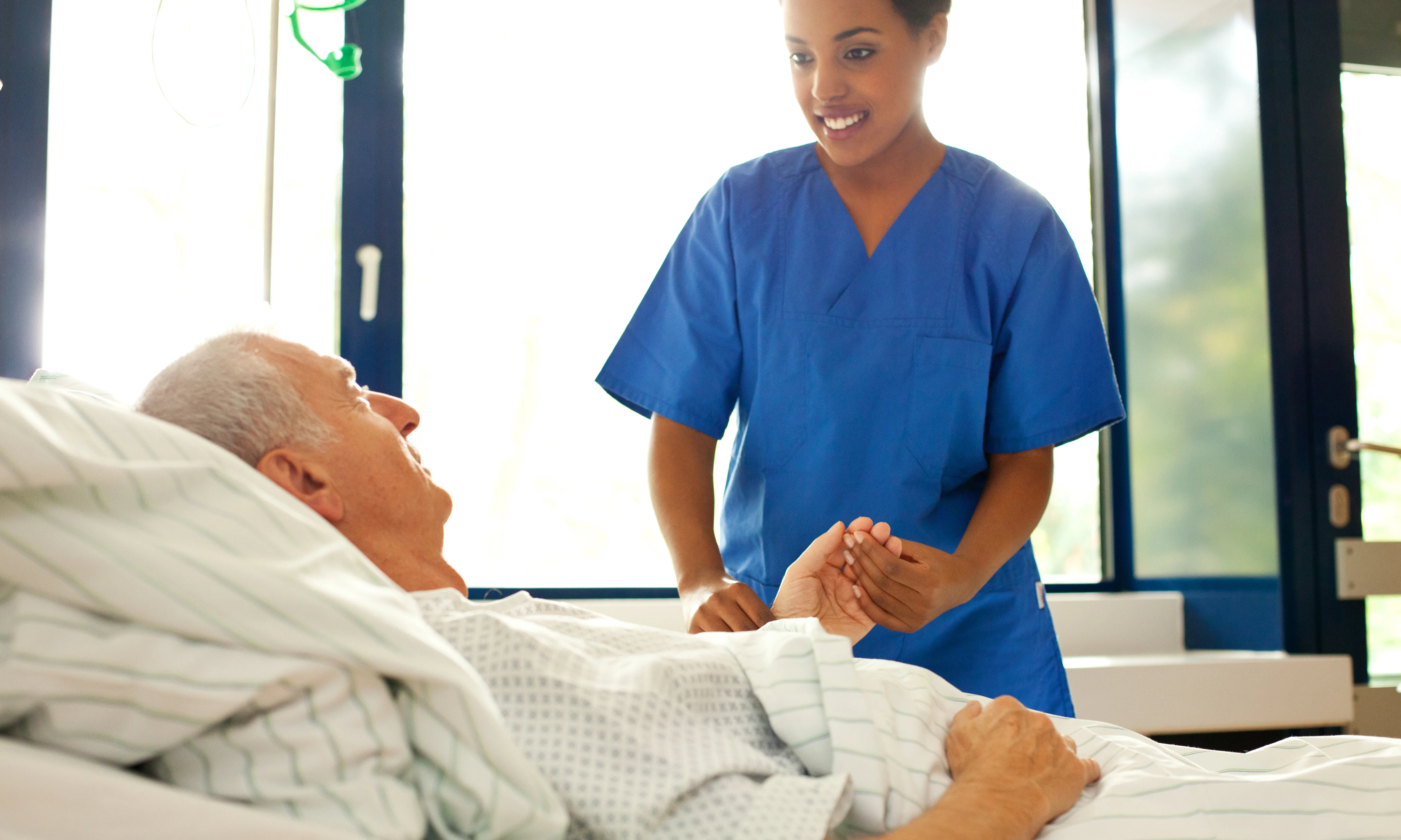En kvinde står over en mand i en hospitalsseng